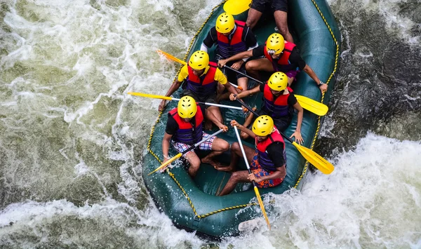 A group of men and women white water rafting