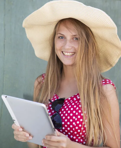 Happy girl in hat holding the tablet computer