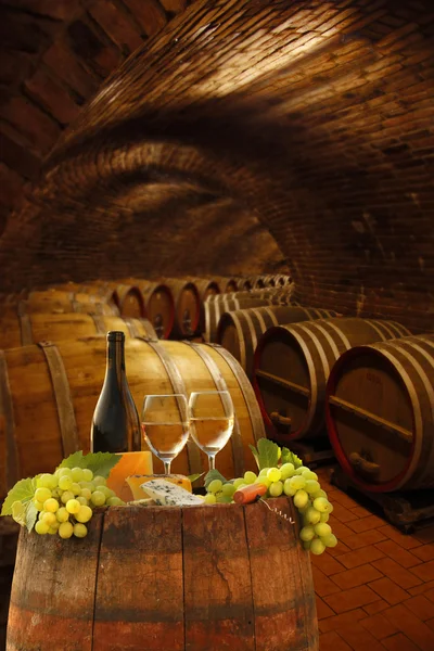 Wine cellar with glasses of white wine against wine barrels