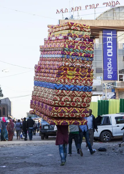 Man carries pile of foam mattresses in Merkato market. Addis Aba