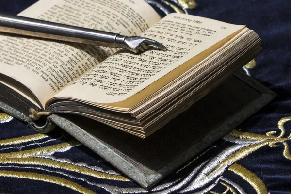 Open bible book in Hebrew with silver pointing hand stick