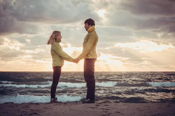 Couple Man and Woman in Love standing on Beach seaside holding hand in hand with Beautiful Sunset sky scenery People Romantic relationship and Friendship concept trendy moody colors