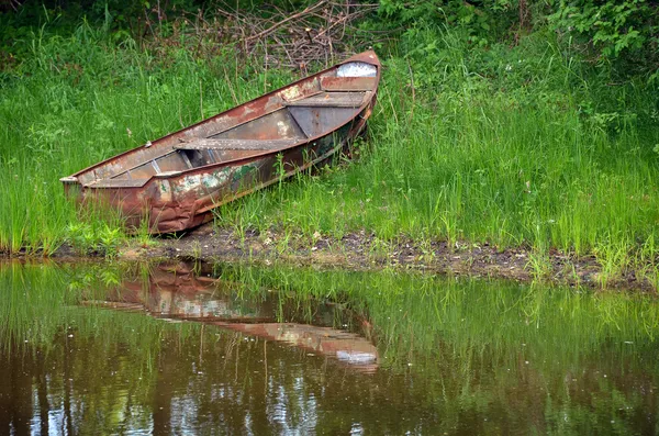 Rusty row boat in weeds