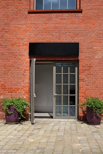 Glass door in brick wall with two flowerpots