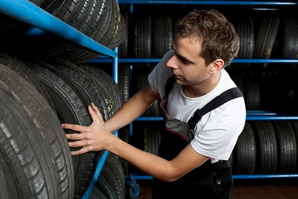 Auto mechanic choosing tire in car service