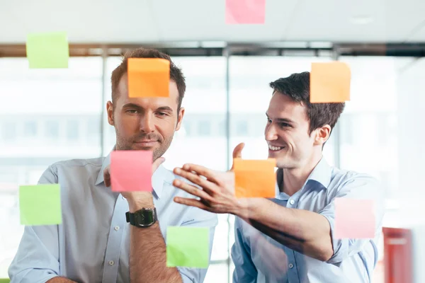 Businessmen discussing ideas on sticky notes