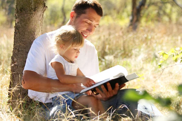 Young father with his little daughter reads the Bible