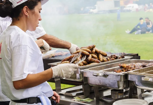 Woman and man handling big sausages and meat