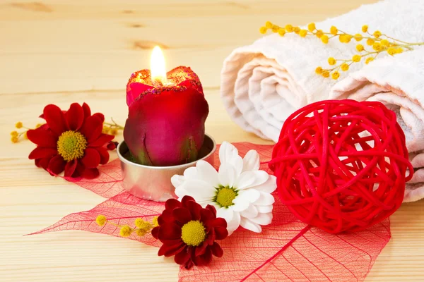Burning aroma candle, spa stuff and flowers on a wooden background