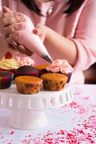 Hands decorating cupcakes