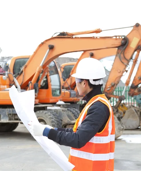 Road construction worker in front of excavator