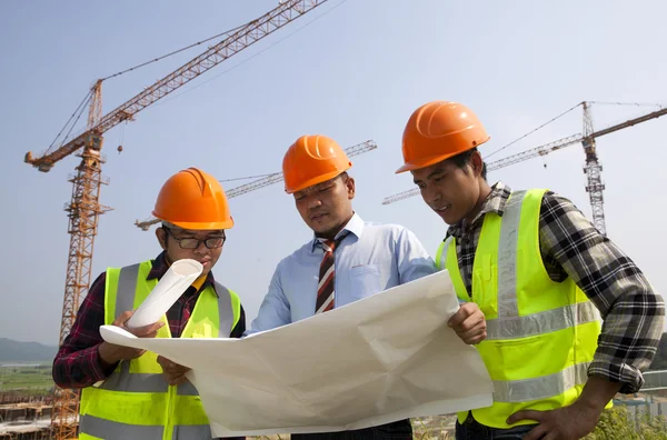 Architects at a construction site looking at blueprint