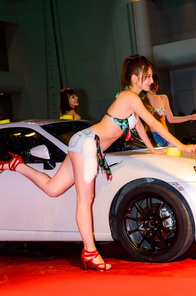 Show Beautiful bikini models wash a car.