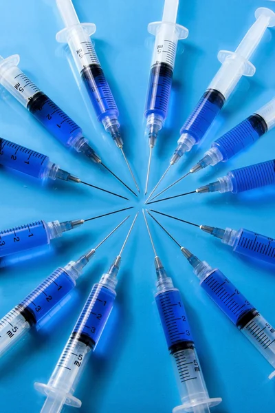 Medical Syringes forming a circle on blue background