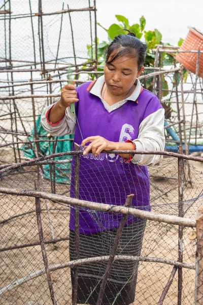 Woman fishermen is weaving fish-trap