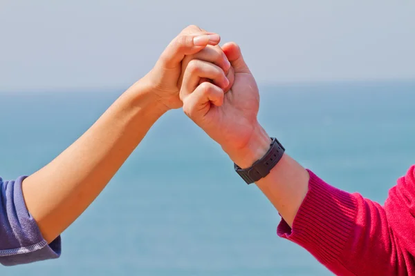 Man and woman hands touch in gentle, soft way on blue sunny sky.