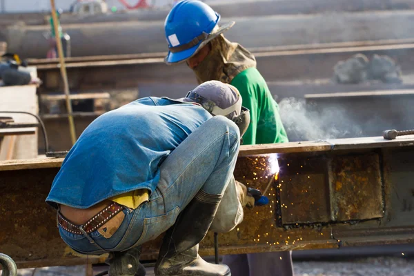 Outdoor worker with protective mask welding metal and sparks