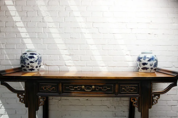 Traditional Chinese vase on a wooden table against a white wall