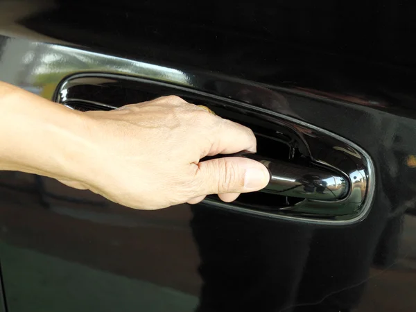 Hand is going to pull a car's door handle