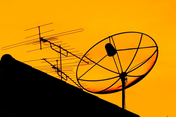 Satellite dish and home TV antenna in the evening
