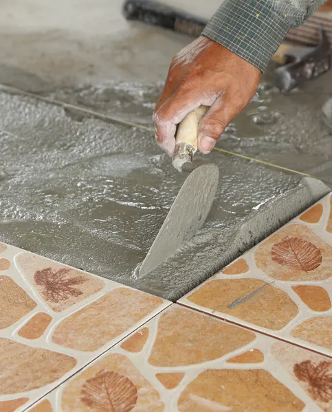 Handyman laying tile, trowel with mortar