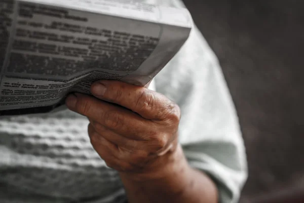 Newspaper in the hand of old woman (blurred russian font)