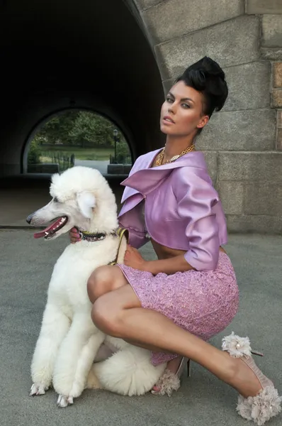 Model holding a white dog wearing pink couture designer clothes