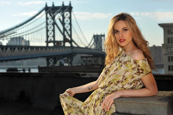 Portrait of fashion model posing sexy, wearing long evening dress on rooftop location with metal bridge construction on background