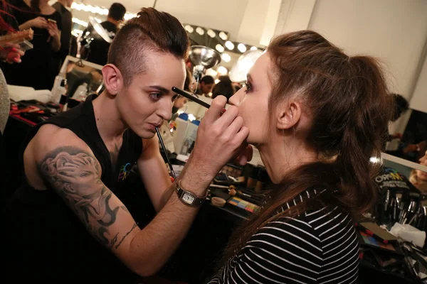 Make-up artist applying lipstick to model face