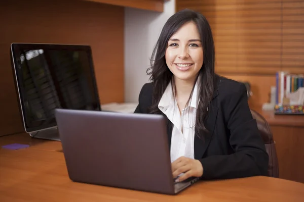 Businesswoman sitting at table in office lobby and using laptop