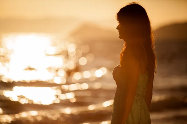 Young woman on the beach at sunset