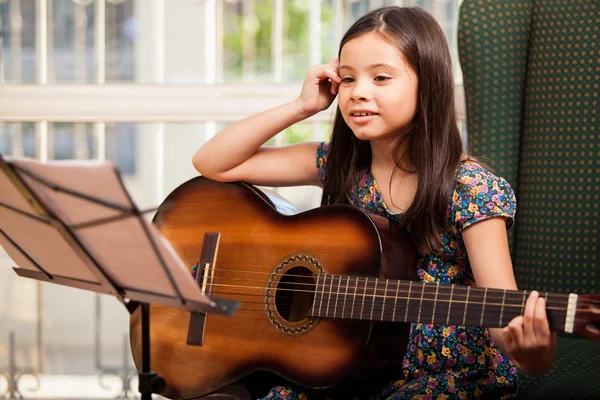 Little girl playing guitar at home