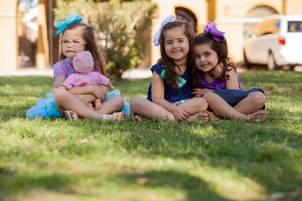 Pretty little girl playing with a doll and hanging out with her friends at a park