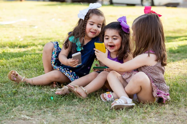 Funny little girls sharing some stuff from their smart phones and having fun