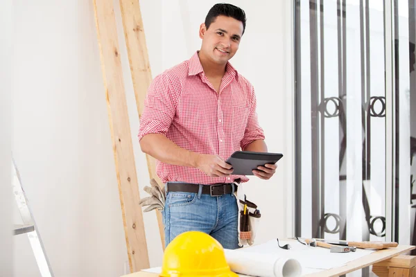 Handsome young contractor using a tablet computer at work