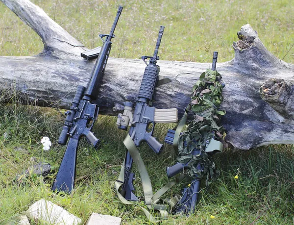 Military weapons for airsoft in a clearing near a wood