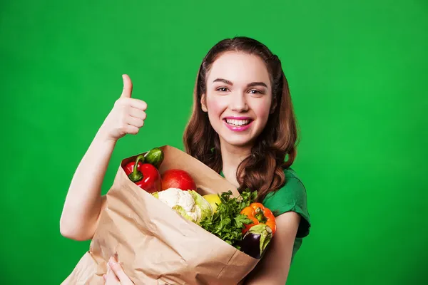 Young smiling woman with a paper bag of vegetables