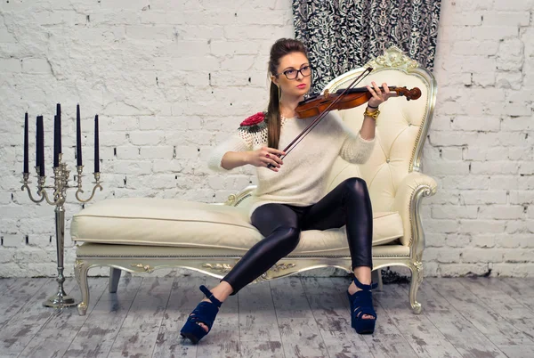 Girl playing the violin on a leather couch