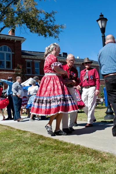Senior Citizen Couple Square Dances At Outdoor Event