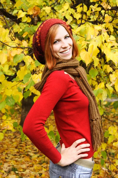 Young redhead girl in warm autumn dress standing and smiling out