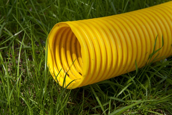 Yellow plastic pipe on green grass