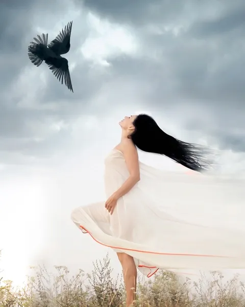 Beautiful young woman waving her hair opposite to flying bird. Freedom concept