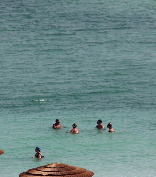 Group of tourists take water treatments at the Dead Sea