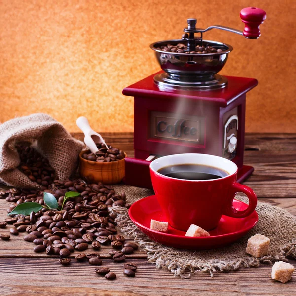 Cup of warm coffee and grinder.