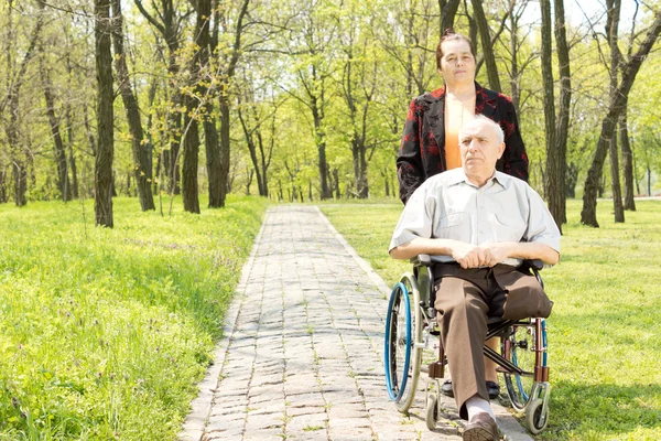 走在轮椅上的残疾的男人的妻子 - 图库照片Va