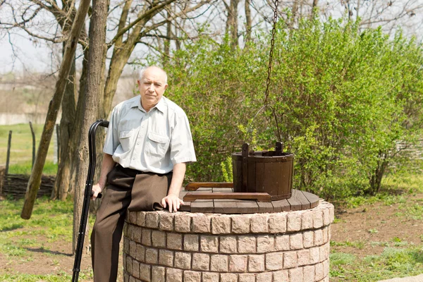One legged man sitting on an old well