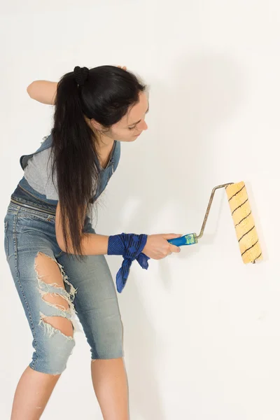 Woman standing painting a wall