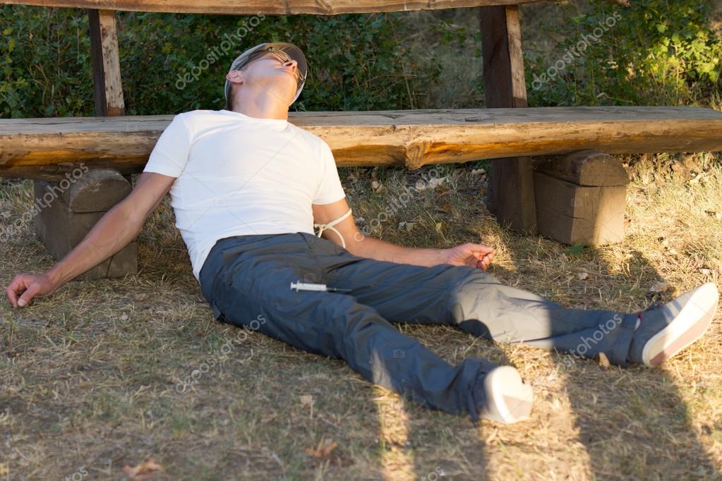 Heroin user lying down leaning on a bench — Stock Photo 