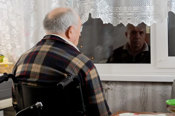 Elderly man in a wheelchair waiting at a window