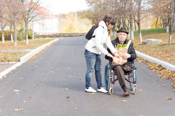 Daughter handing an elderly disabled man groceries